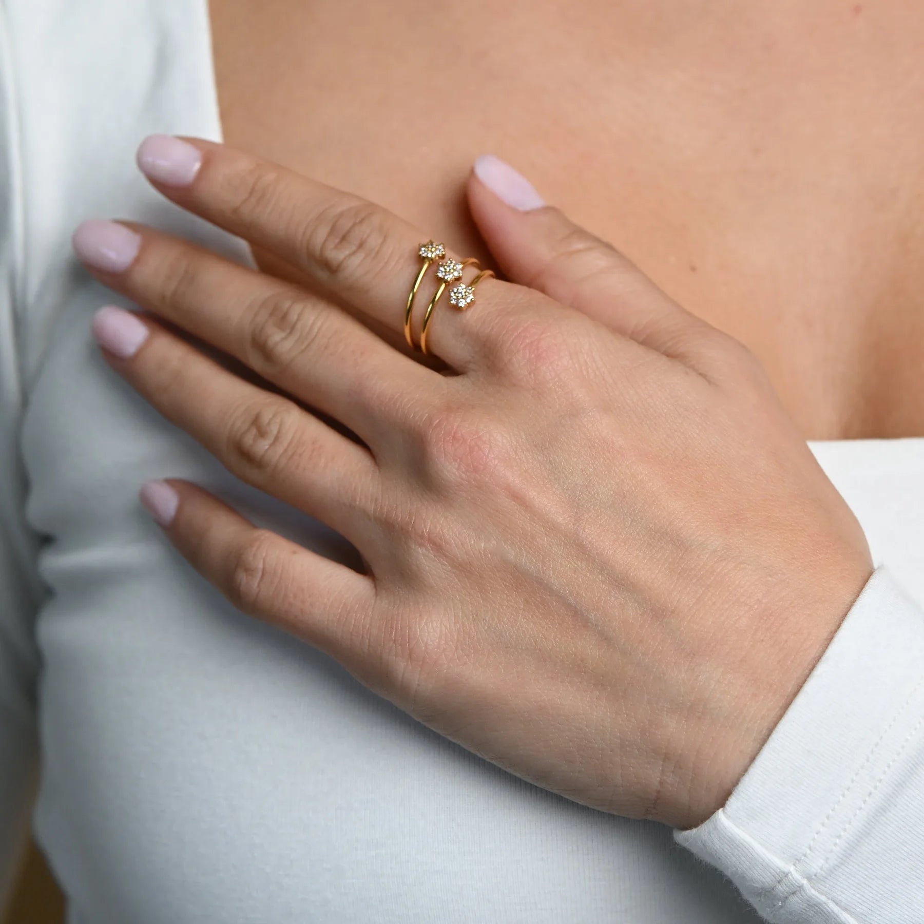A hand wearing delicate 22K gold diamond rings by Omar Jewelers