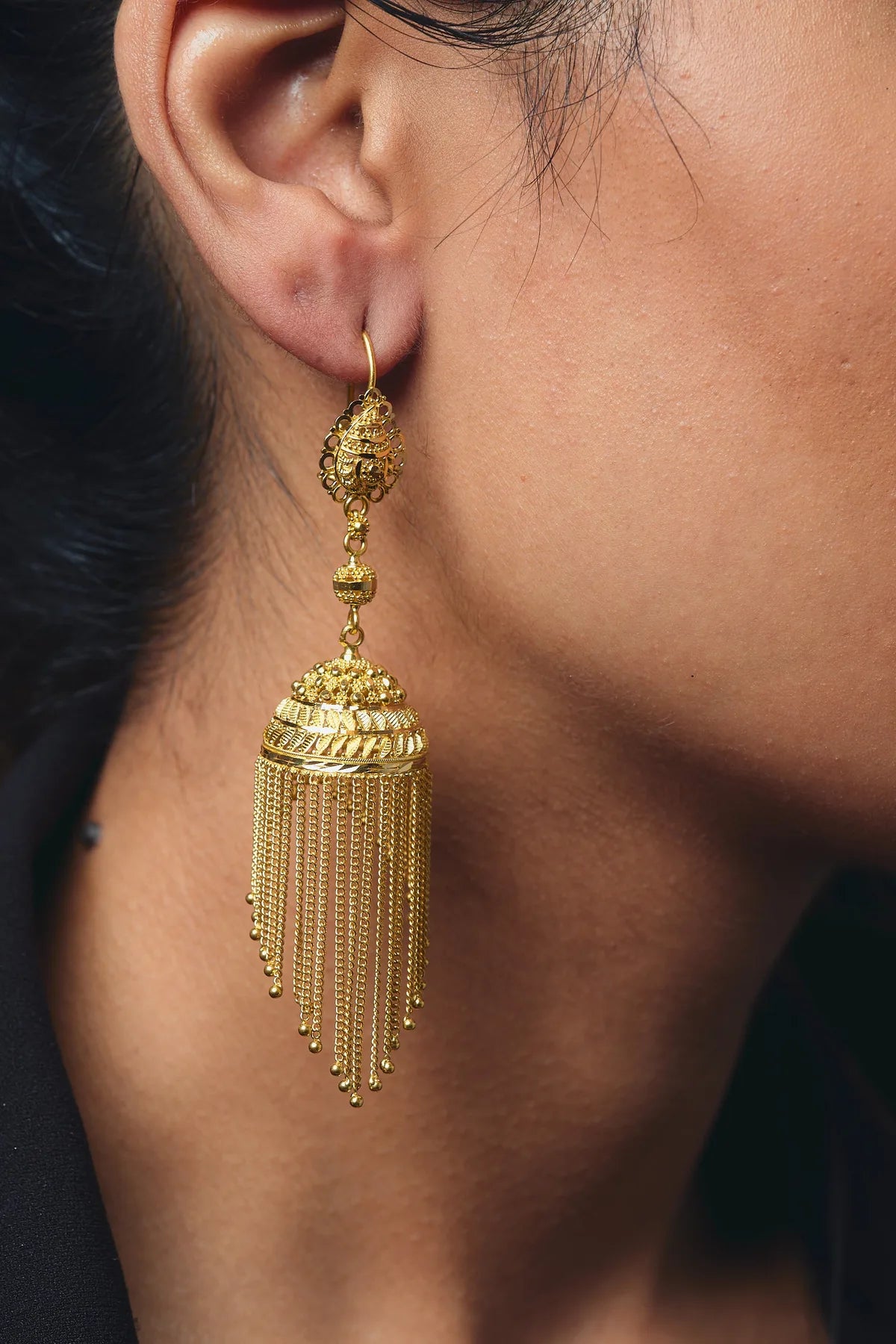 A hand-finished 22K gold tassel earring worn